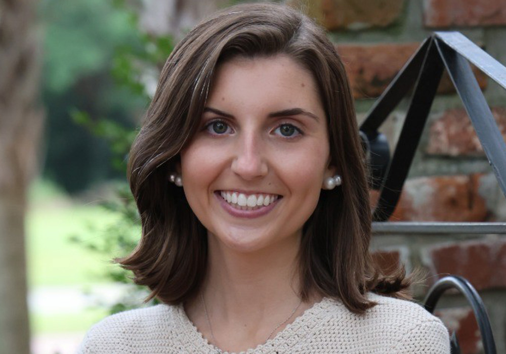 head and shoulders photo of a woman in front of a brick and iron gate