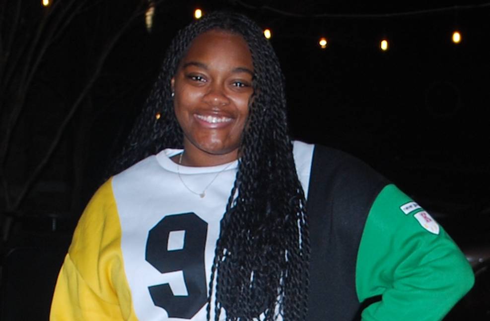 A girl stands smiling facing the camera