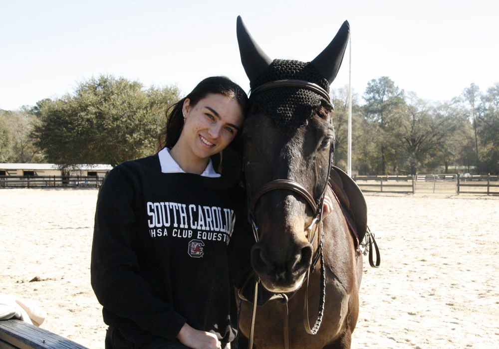 A girl smiles with her horse.