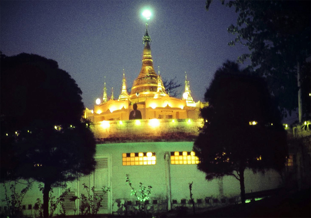 A golden pagoda building with several steeples is lit against evening sky