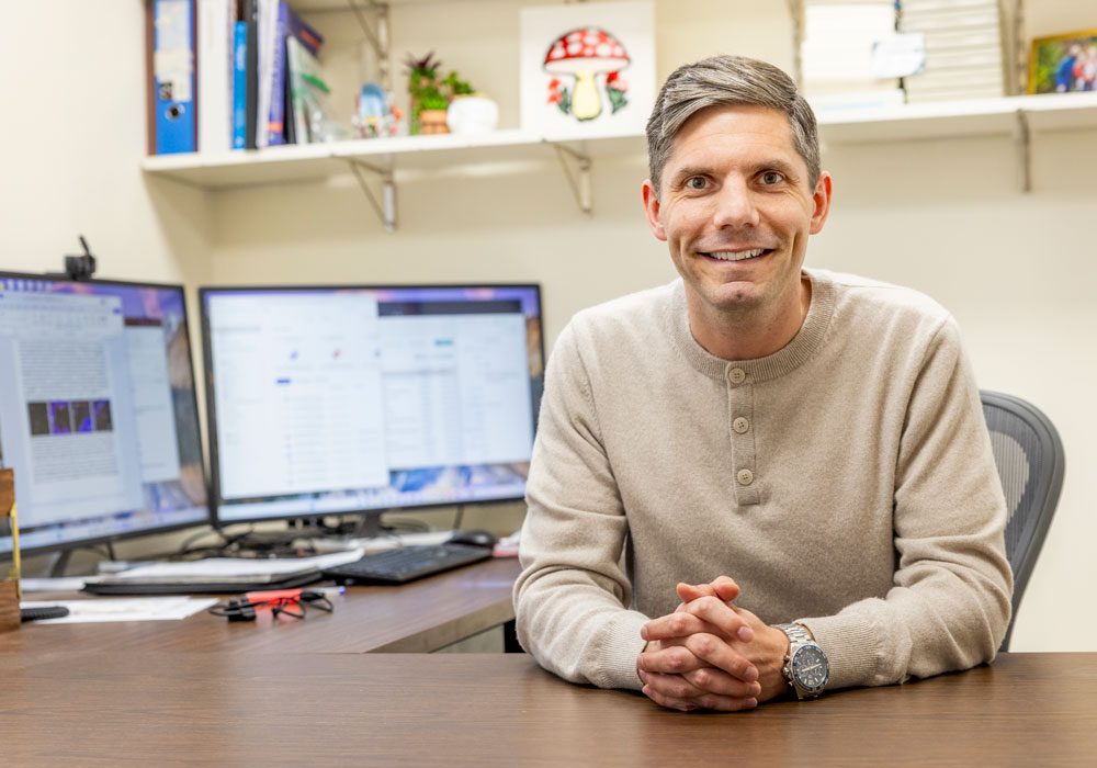Colin Evans smiles at his desk