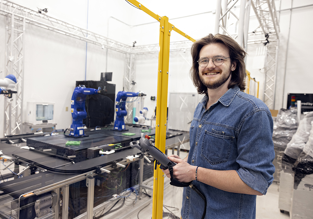 Austin Harper smiles as he works in an industrial engineering lab.