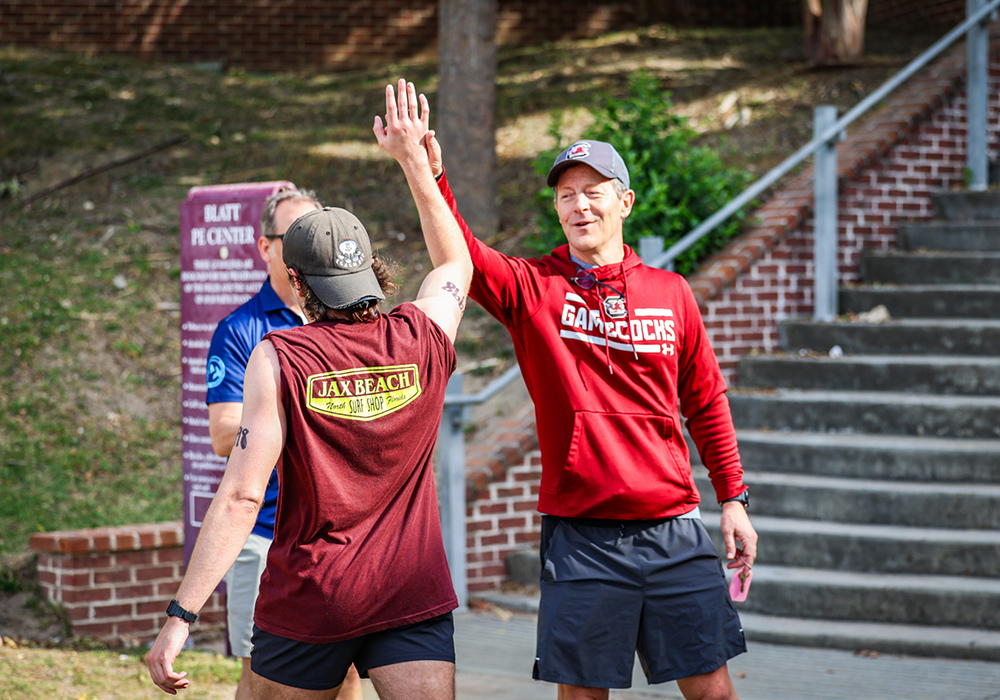 A coach high fives a student runner.