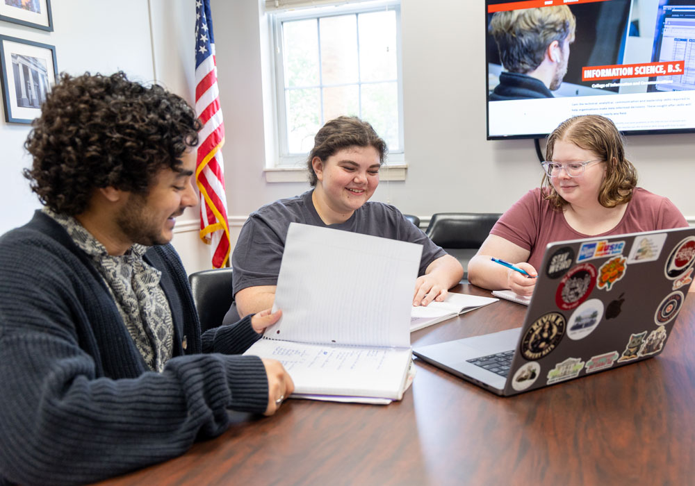Three CIC students study in front of a laptop in a Davis College classroom