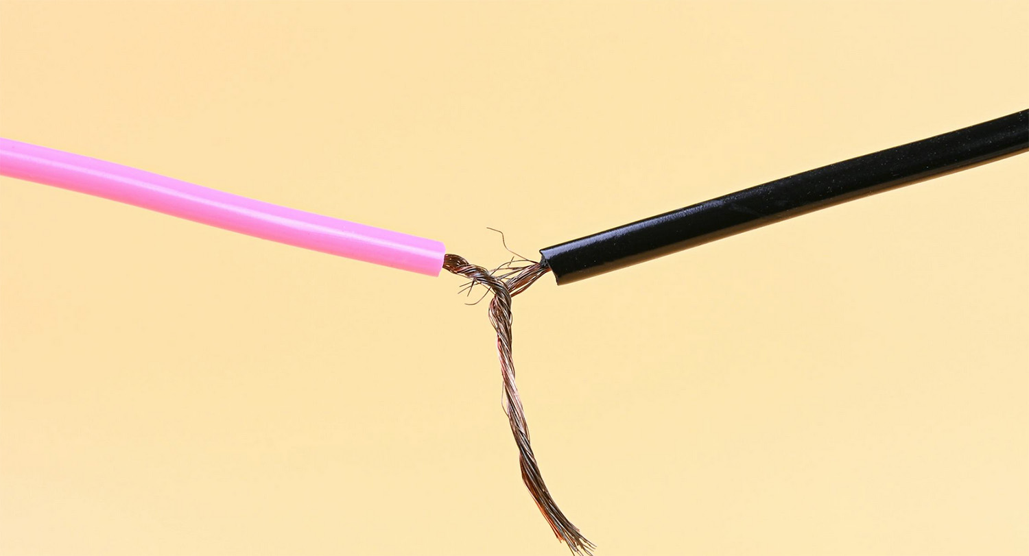 A pink wire (left) is joined with a black wire by twisting inside wiring together