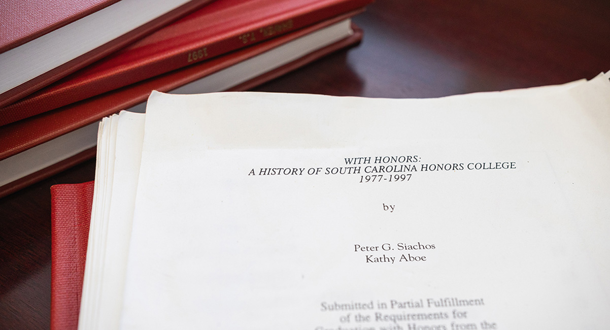 Pages of a thesis document amid a stack of books