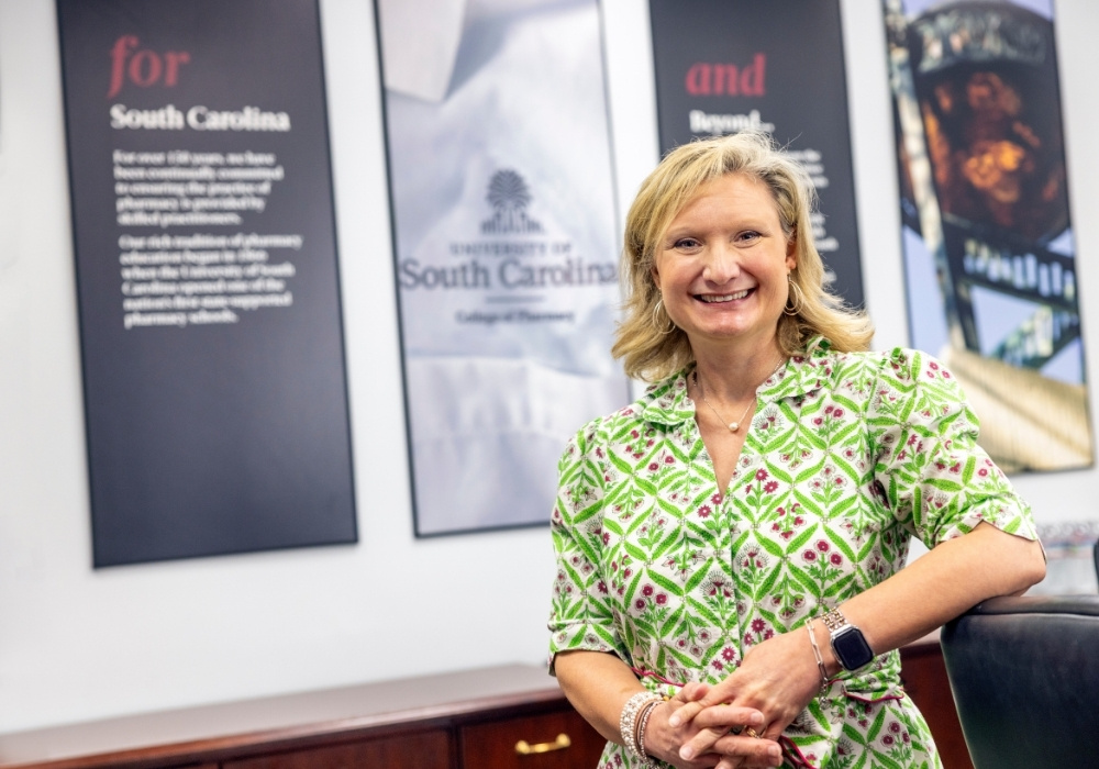 Betsy Blake, pharmacy professor, smiles for a photo in an academic building.