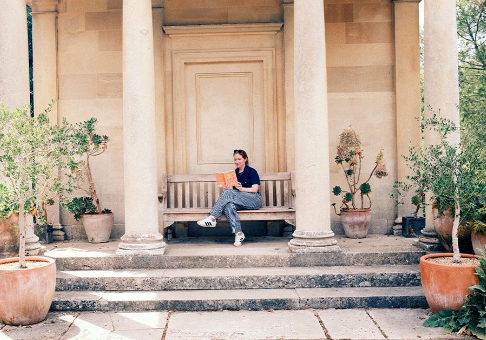 Ashley Poston sits on a bench in an English garden and reads her new book.