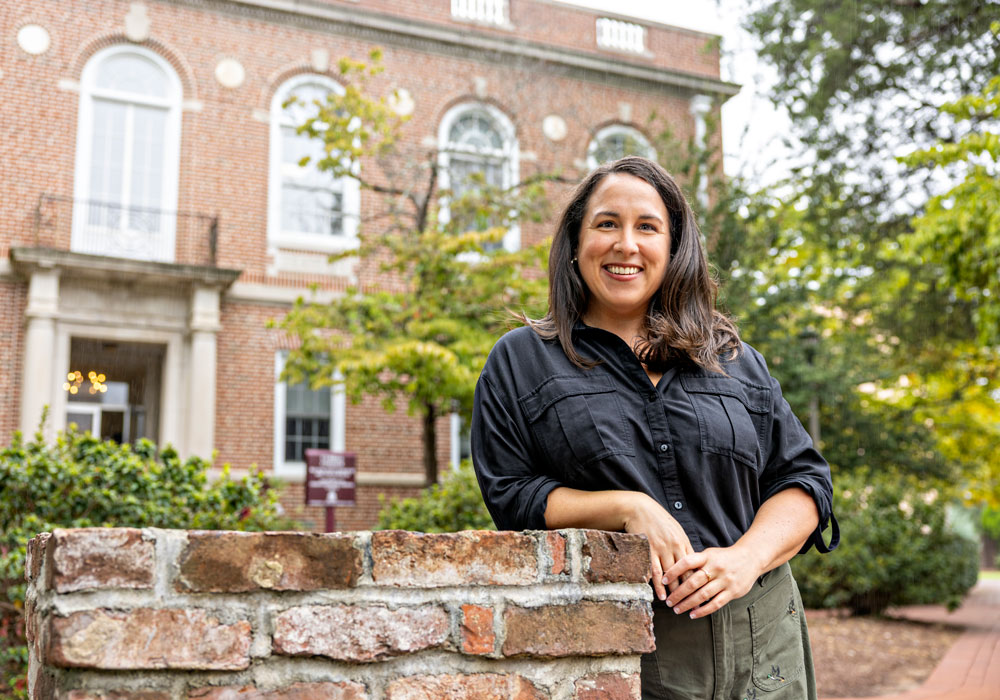 Woman in black shirt smiling against brick building with ivy
