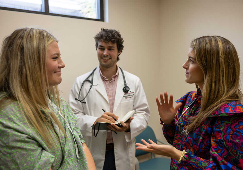 Physician and medical student meet with patient