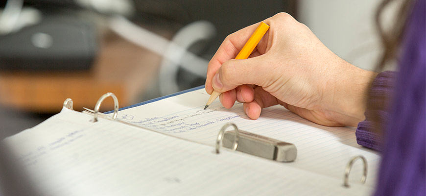 close up of a student taking notes with a pencil