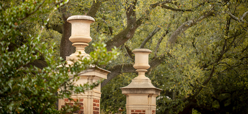 Two gates separated by greenery welcoming visitors to campus.