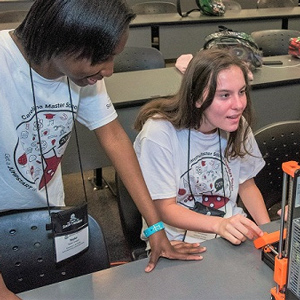 two students operate a 3-d printer