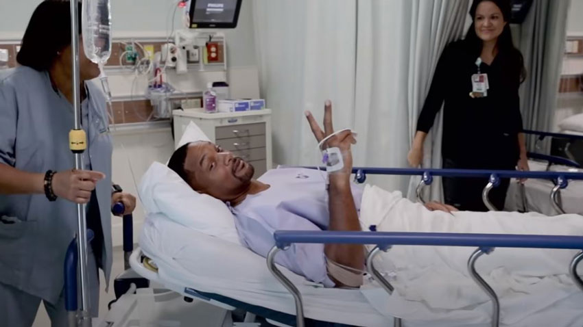 Will Smith gives a peace sign while lying on a hospital gurney