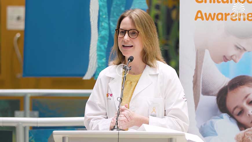 Dr. Anna Hoppmann stands at podium to talk about S.C. Pediatric Cancer Report