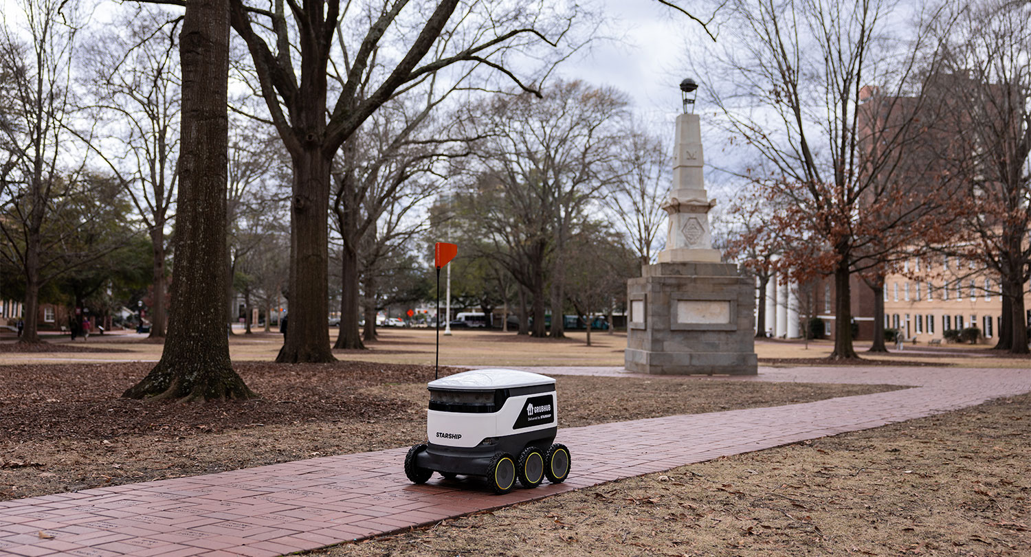 A Starship delivery robot rolling past the Maxcy Monument on the Horseshoe