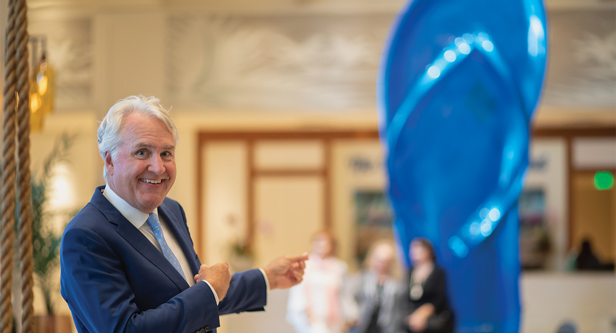 Jim Wiseman pointing at a large blue flip flop 