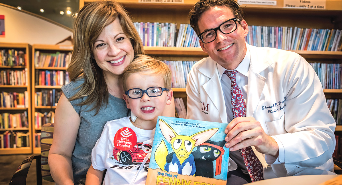 Dr. Buchannan holding his book with a little boy and his mom