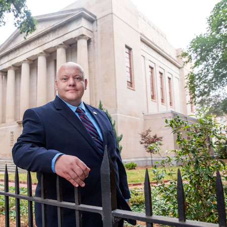 James Hull wearing a dark suit stands outside the War Memorial Building on the UofSC campus.