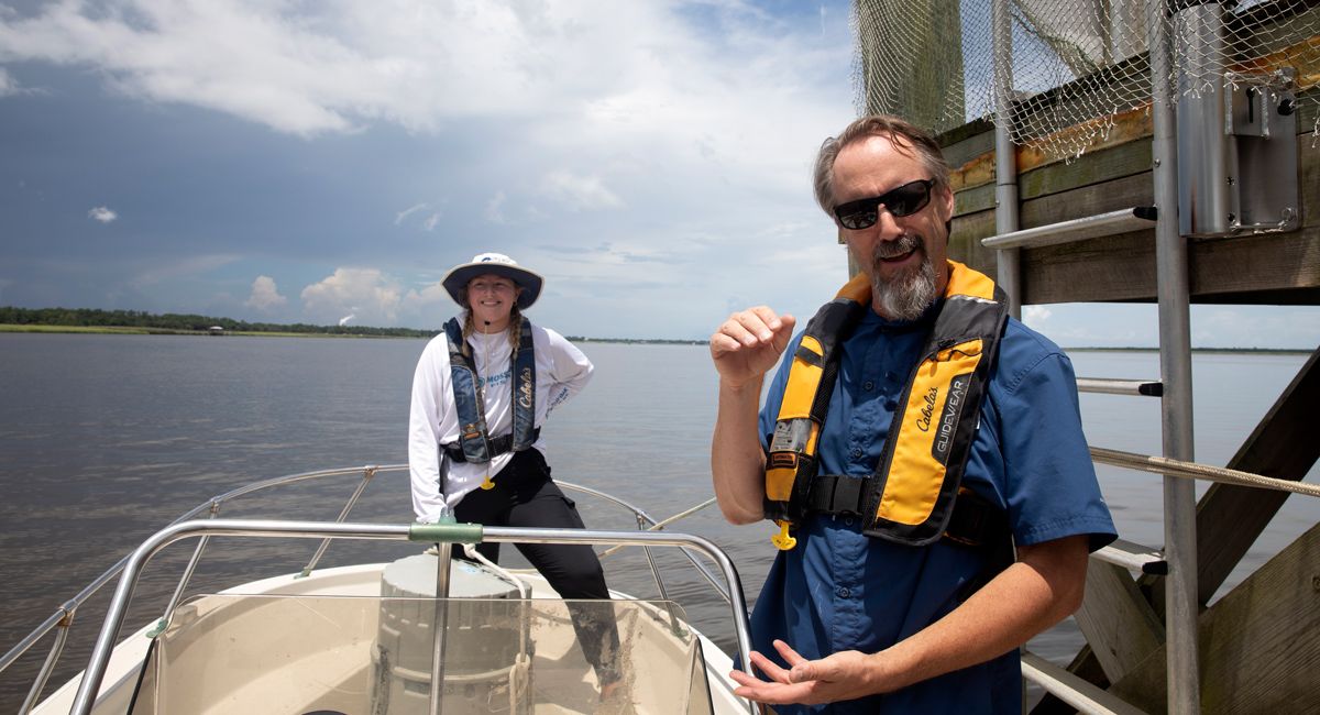 Camille Wheeler and Erik Smith in a boat at a instrument platform in Winyah Bay.