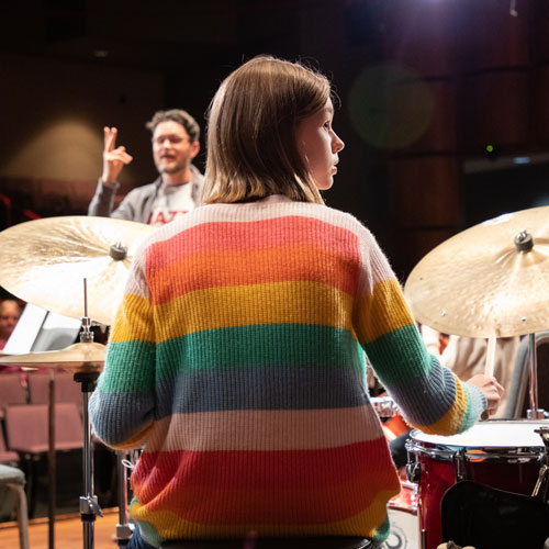 Girl plays drums on stage.