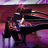 Two people playing pianos on stage.{