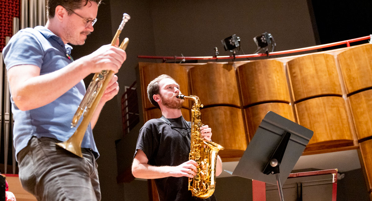 Professor watches as saxophonist plays during rehearsal