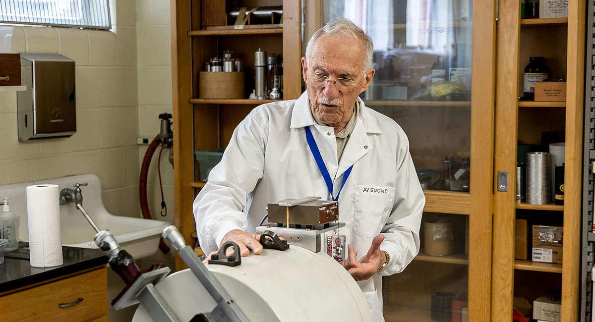 Frank Avignone in a white lab coat working with lab machine.