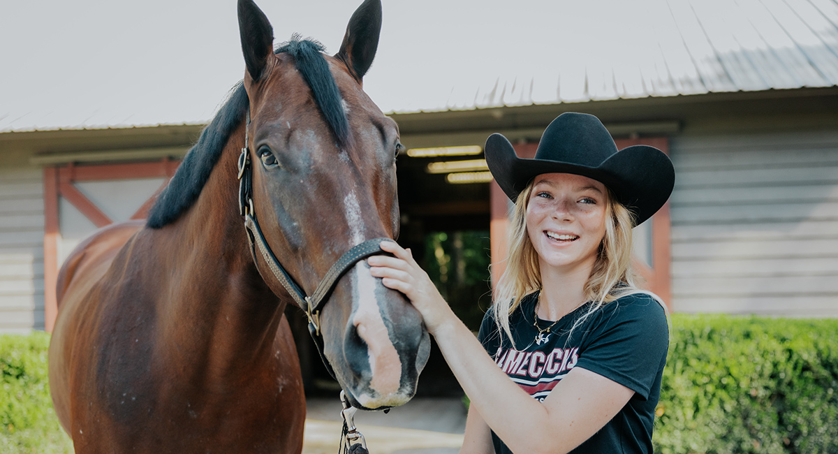 Ruby Voortmeyer poses with an equestrian team horse.