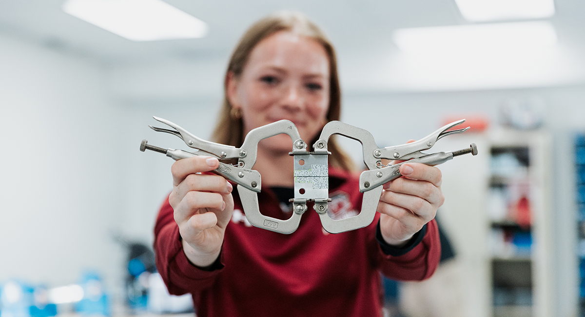 Ruby Voortmeyer holds a testing fixture in the laboratory.