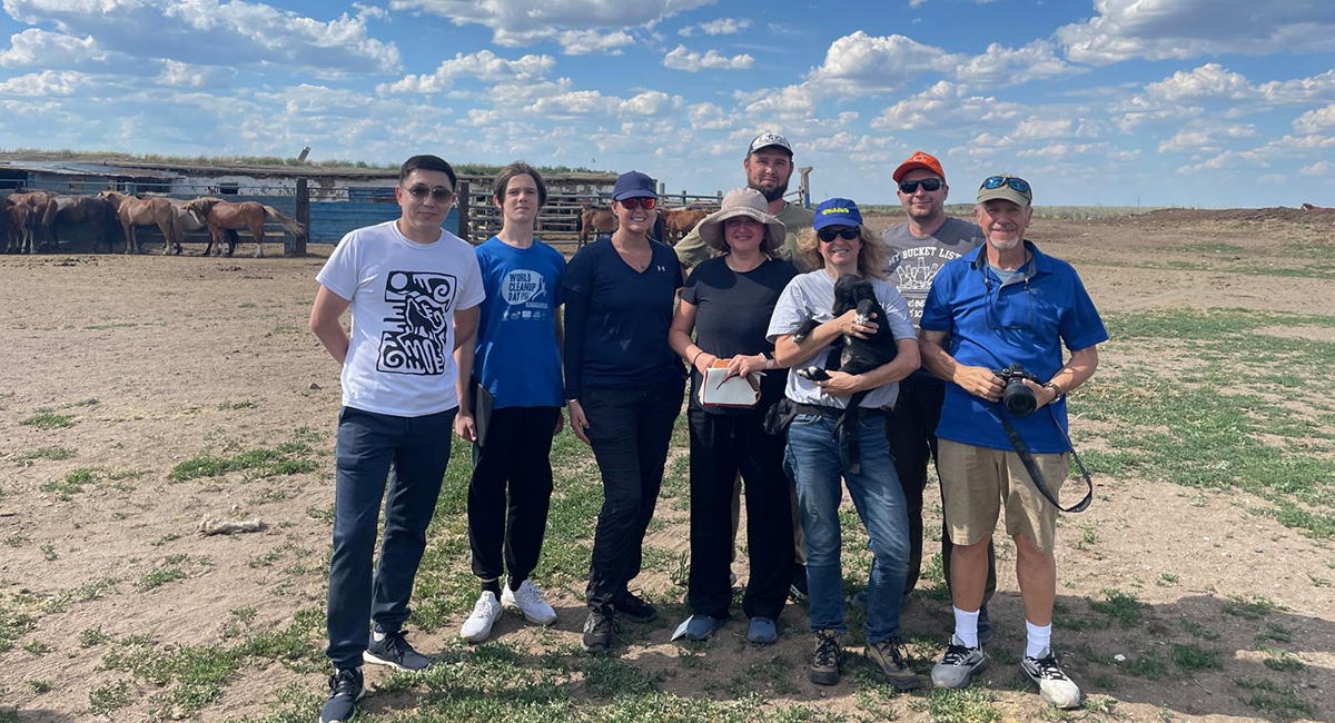 Group of eight people in remote Kazakhstan field.