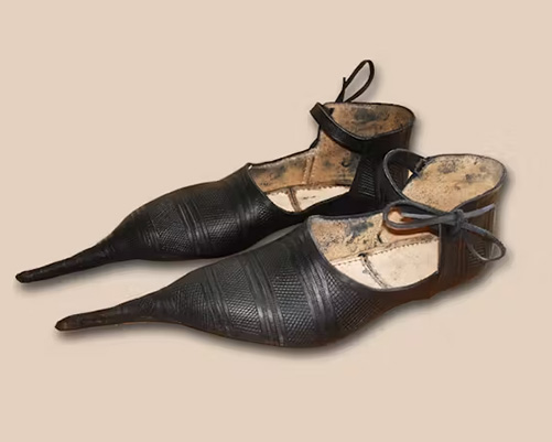 A black leather pair of poulaines with extra long pointy toes