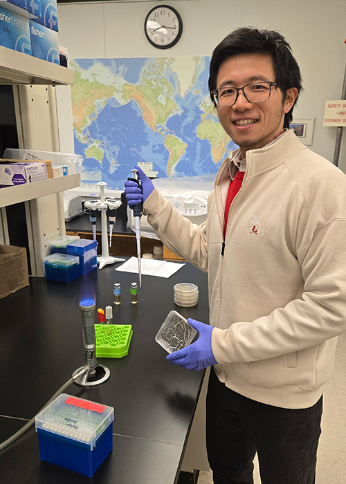 Smiling Asian man with glasses in his laboratory