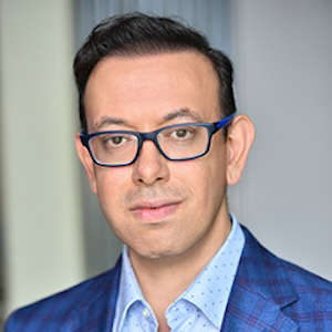 portrait of man in blue blazer and shirt wearing glasses 