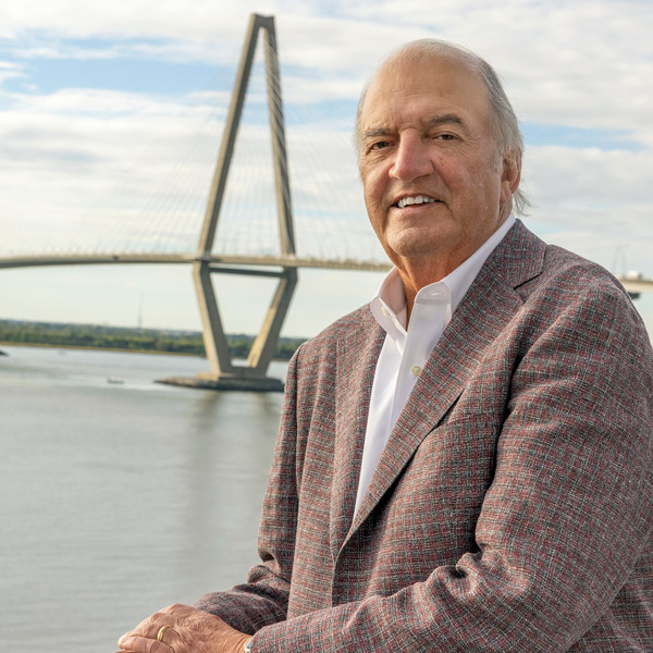 a man leans on a railing with a cable-stayed bridge in the background