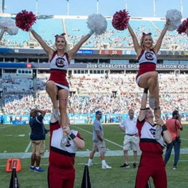 2 UofSC cheerleaders waving their pom poms at the Bank of America Stadium in Charlotte.