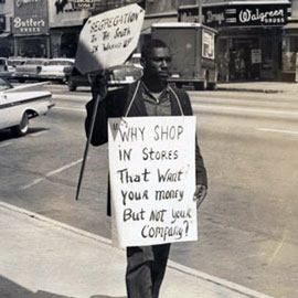 1960s civil rights protestor carries signs denouncing segregation