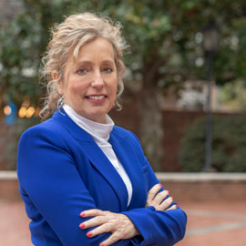 Deborah Beck wearing a blue suit stands near the student health center