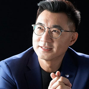 Johnny Chiang looking up, wearing glasses and blue sports jacket
