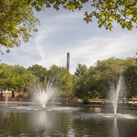 Fountains on campus in front of Thomas Cooper Library with campus smokestack in background.