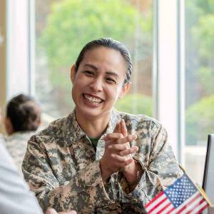 Female veteran in in uniform sitting at a table smiling