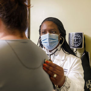 Family nurse practitioner Tamieka Alston-Gibson listens to a patient's back through a stethoscope. 