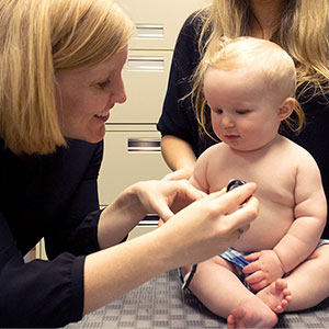 Researcher listening to a baby's heart.