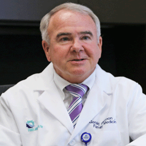 photo of Dr. Gerald Harmon in medical coat with purple-striped tie