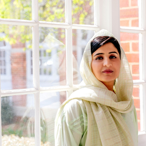 a woman stands in front of a window in traditional Pakistani dress
