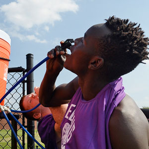 Teen athlete drinks water out of gatorade tub