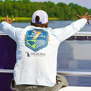 a man wearing a ball cap and T-shirt that reads South Carolina 7 sits on a boat in the Cooper River