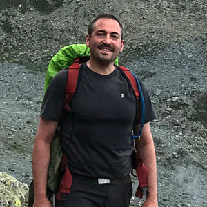 Besim Dragovic standing with backpack in the Swiss Alps.