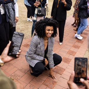 Honoree Amber Guyton kneels over her brick and smiles