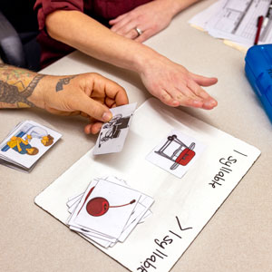 A close-up of a patient's hands and a speech-language pathologist's hands as they do a flashcard activity together.